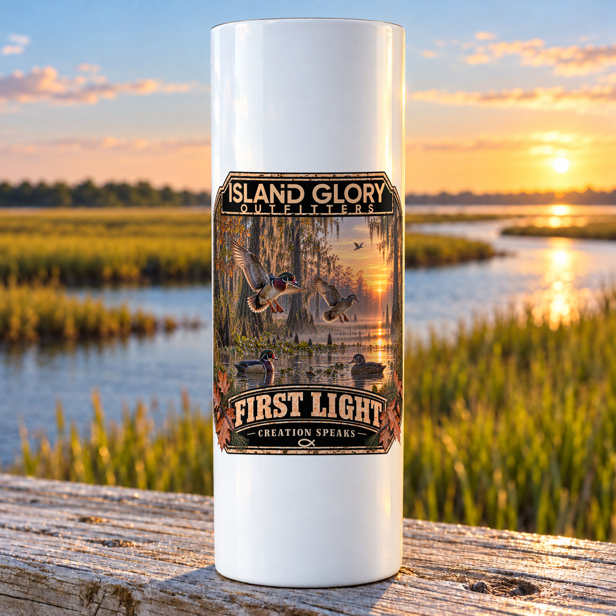 First Light — Wood Ducks design on a white Hogg 20 oz skinny tumbler beside an Eastern North Carolina coastal marsh.