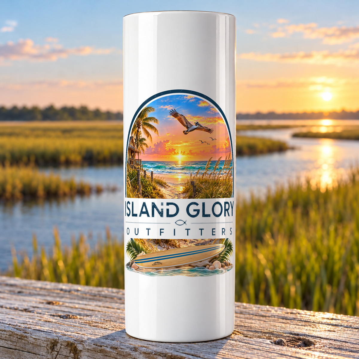 Island Morning design on a white Hogg 20 oz skinny tumbler beside an Eastern North Carolina coastal marsh.